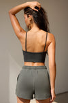 Back view of model posing in the fitted and stretchy vintage black flexrib Strappy Crop Tank with thin straps and a low back