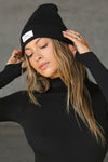 Front view of model posing in the warm knit black Official Beanie with a joah brown logo patch on the front