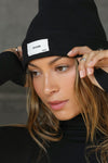 Close up front view of model posing in the warm knit black Official Beanie with a joah brown logo patch on the front