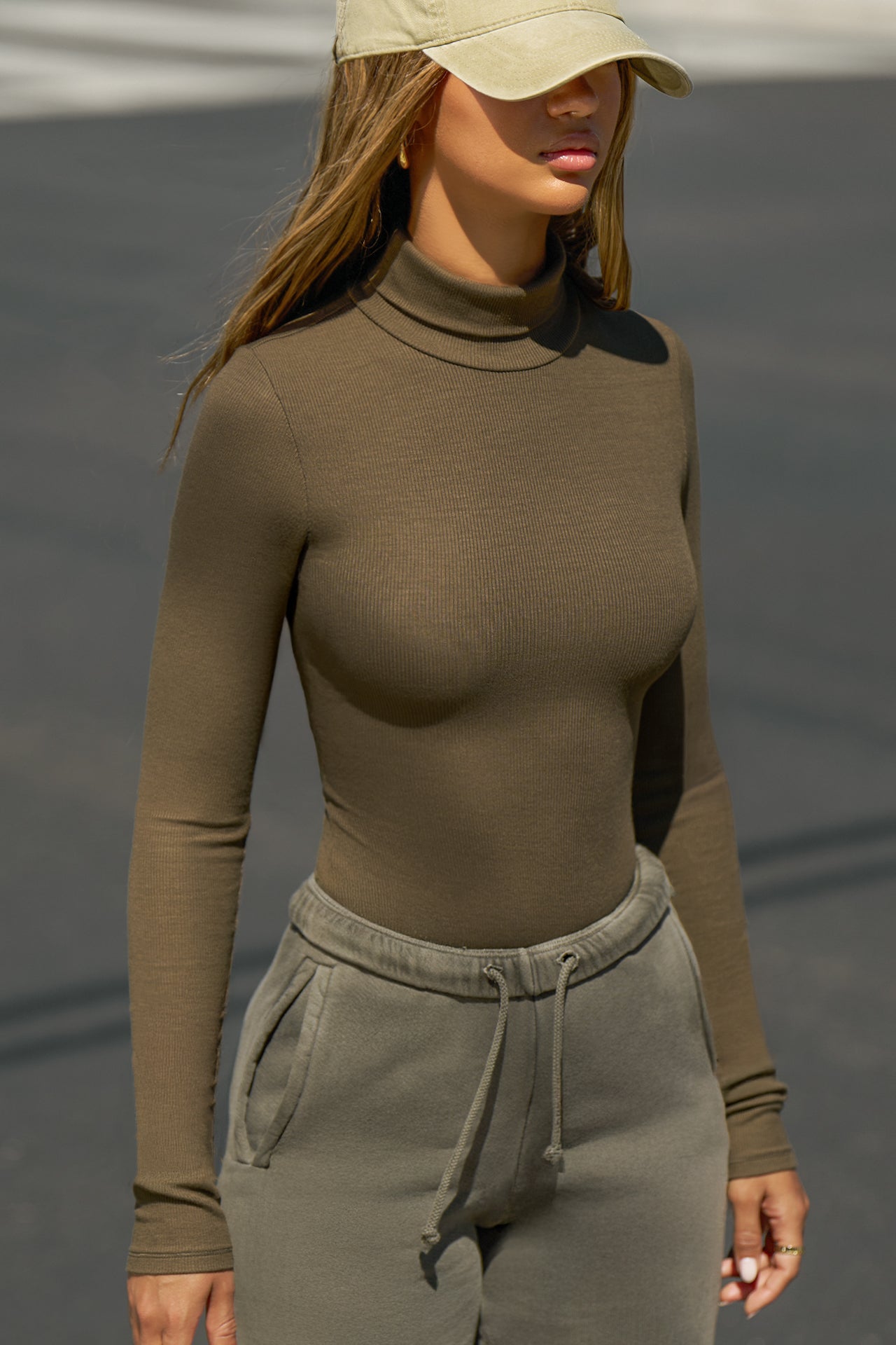 Front view of model posing outside in the street in the form-fitting and stretchy woodland rib Classic Turtleneck long sleeve top