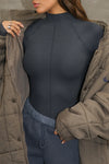 Close up front view of model posing in the fitted vintage navy flexrib Stitch Mock Neck Long Sleeve top with tonal stitching on the front, a mock neckline and thumbholes in the cuffs
