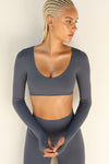 Front view of model posing the ultra cropped sueded navy Crop V Neck Long Sleeve top with with thumbholes