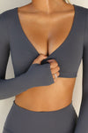 Close up detail front view of model posing the ultra cropped sueded navy Crop V Neck Long Sleeve top with with thumbholes