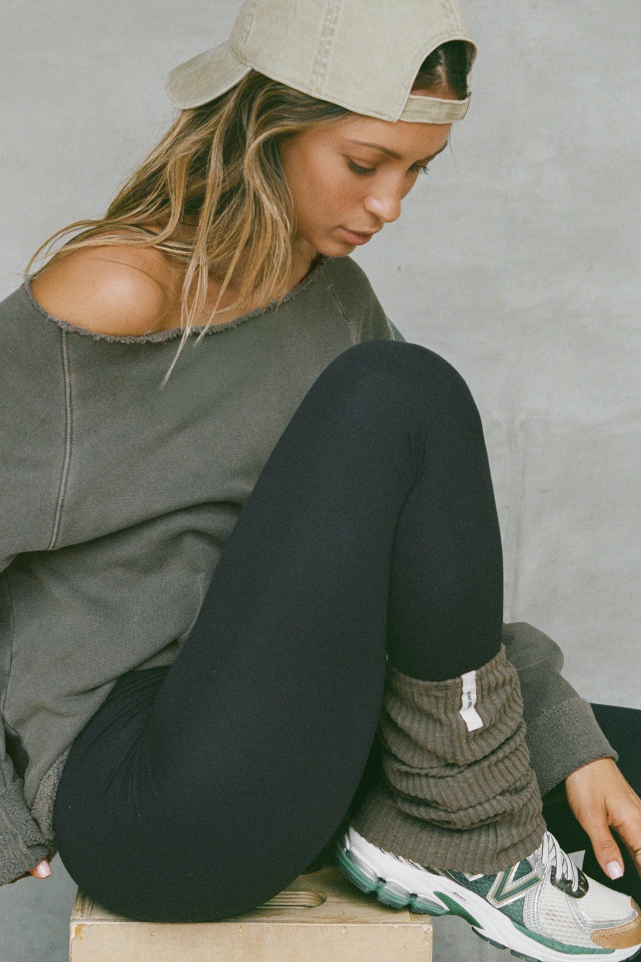 Side view of model posing in slouchy, pull on army luxe knit Leg Warmers that can be worn pulled up on scrunched down