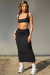 Full body front view of model  posing in the fitted black model Foldover Maxi Skirt with an adjustable fold over waistband