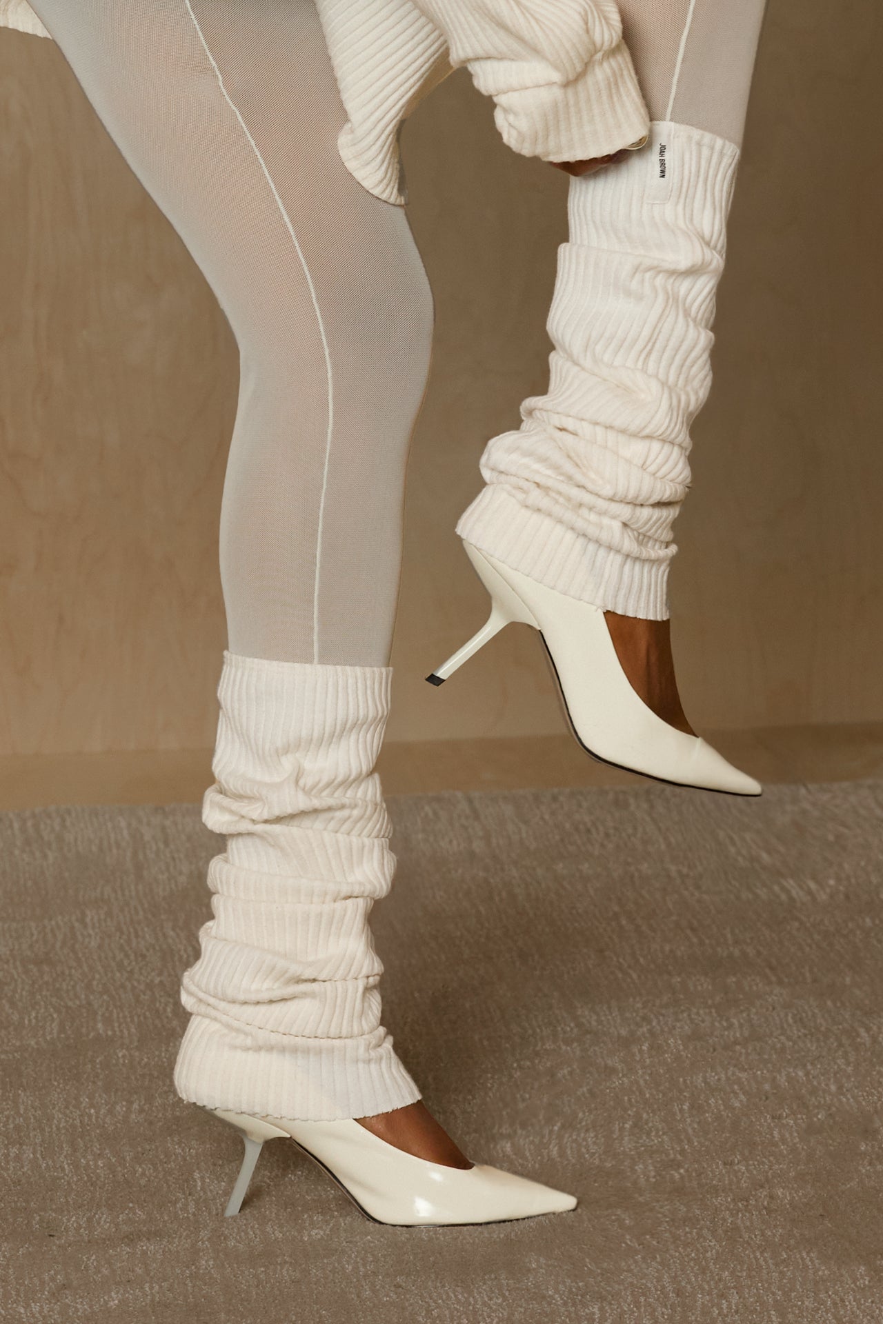 Close up side view of model adjusting the slouchy, pull on natural luxe knit Leg Warmers that can be worn pulled up on scrunched down