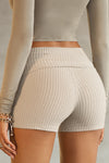 Close up back view of model from the waist down posing in the fitted, soft ecru luxe knit Foldover Short with a foldover waist band that can be worn high, low or mid-rise