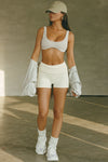 Full body front view of model posing in the fitted, soft natural luxe knit Foldover Short with a foldover waist band that can be worn high, low or mid-rise