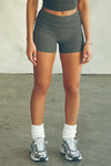 Front view of model from the waist down posing in the fitted, soft charcoal luxe knit Foldover Short with a foldover waist band that can be worn high, low or mid-rise