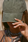 Close up detail front view of model wearing the six-panel washed green Official Cap with a curved brim and an embroidered upside down Joah Brown logo on the front