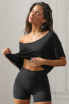 Front view of model posing in the cropped, loose fitting black model Slouchy Crop Tee with a wide scoop neckline