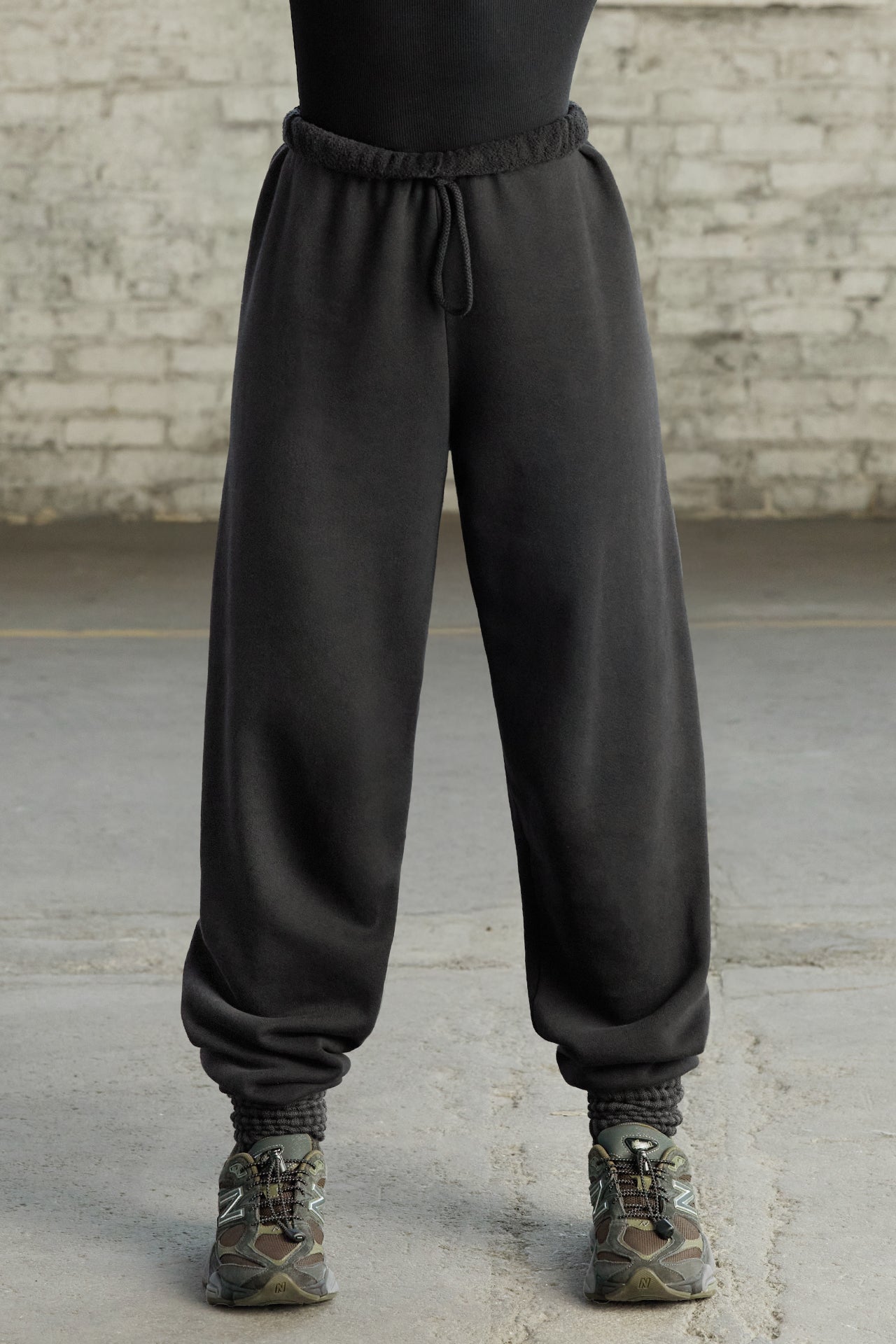 Front view of model from the waist down wearing the oversized loose fit black french terry Oversized Jogger with an elastic waistband and ankle cuffs