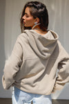 Back view of model posing in the oversized comfortable sand french terry Oversized Zip Hoodie with a full length front zip closure, side pockets and thumbholes in the fitted cuffs
