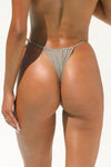 back view of model posing in the minimal coverage dove Side Tie string bikini bottoms with an adjustable tie on the left side