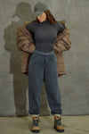 Full body front view of model posing in the fitted vintage navy flexrib Stitch Mock Neck Long Sleeve top with tonal stitching on the front, a mock neckline and thumbholes in the cuffs