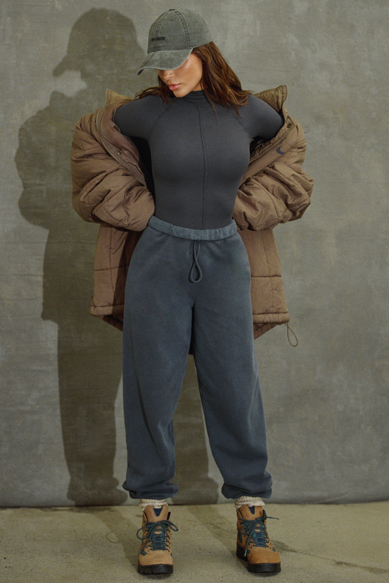 Full body front view of model posing in the fitted vintage navy flexrib Stitch Mock Neck Long Sleeve top with tonal stitching on the front, a mock neckline and thumbholes in the cuffs