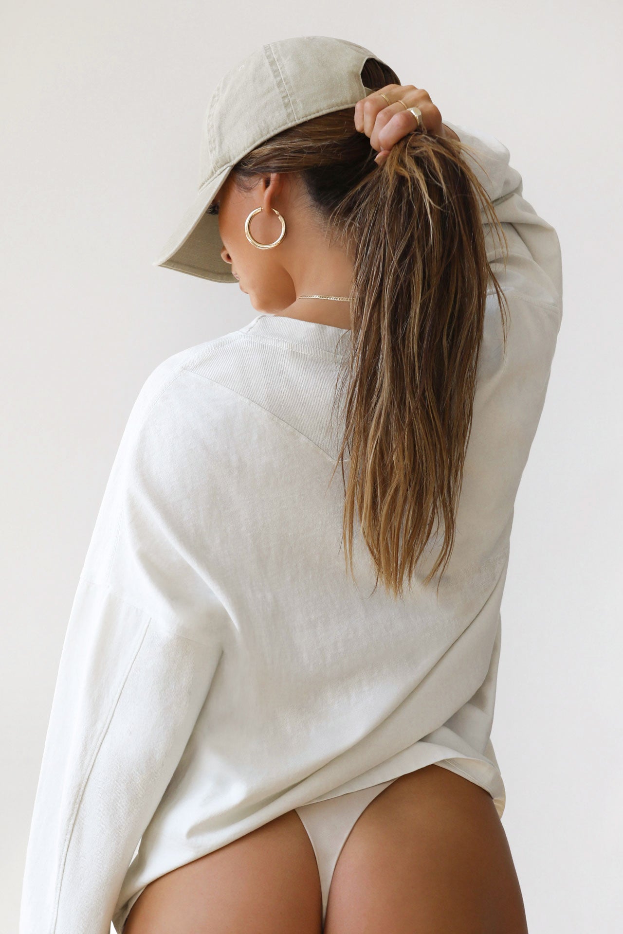 Back view of model posing in oversized fog cotton Vintage Long Sleeve top with a crew neckline and ribbed accents at the upper back