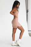 Full body side view of model posing in the form fitting stretchy clay rib mini Slip Dress with thin straps, a u neckline and a tiny side slit at the hem