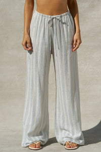 Front view of model from the waist down posing in the relaxed fit lightweight natural white and blue stripe gauze Relaxed Everyday Pant with an elastic waistband and adjustable front tie
