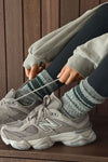 Close up side view of model adjusting the crew-style ribbed and soft heathered charcoal Merino Stripe Sock