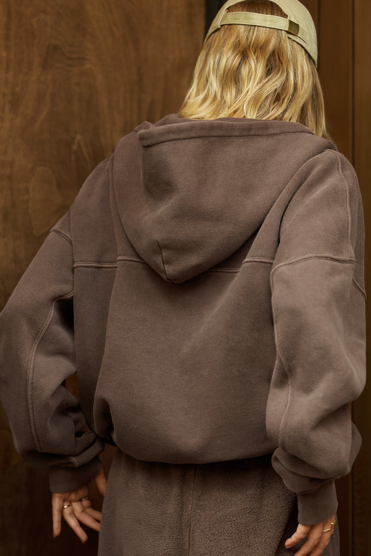 Back view of model posing in the oversized comfortable cedar french terry Oversized Zip Hoodie with a full length front zip closure, side pockets and thumbholes in the fitted cuffs