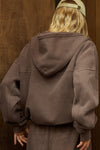 Back view of model posing in the oversized comfortable cedar french terry Oversized Zip Hoodie with a full length front zip closure, side pockets and thumbholes in the fitted cuffs