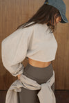 Side view of model posing in the cropped relaxed fit sandstone cotton Slouchy Crop Long Sleeve top with a crew neckline, dropped shoulders and oversized sleeves