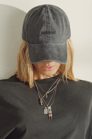 Front view of model wearing the six-panel washed black Official Cap with a curved brim and an embroidered upside down Joah Brown logo on the front
