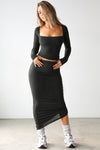Full body front view of model posing in the midi length black modal Cinched Skirt with adjustable side cinching