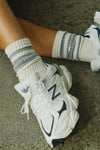 Close up front view of model's feet in New Balance sneaker pair with the crew style ribbed soft grey ash Classic Stripe Sock