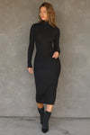 Full body front view of model posing in the fitted black rib Mock Neck Midi Dress with a mock turtleneck neckline, long sleeves and a mid-calf length
