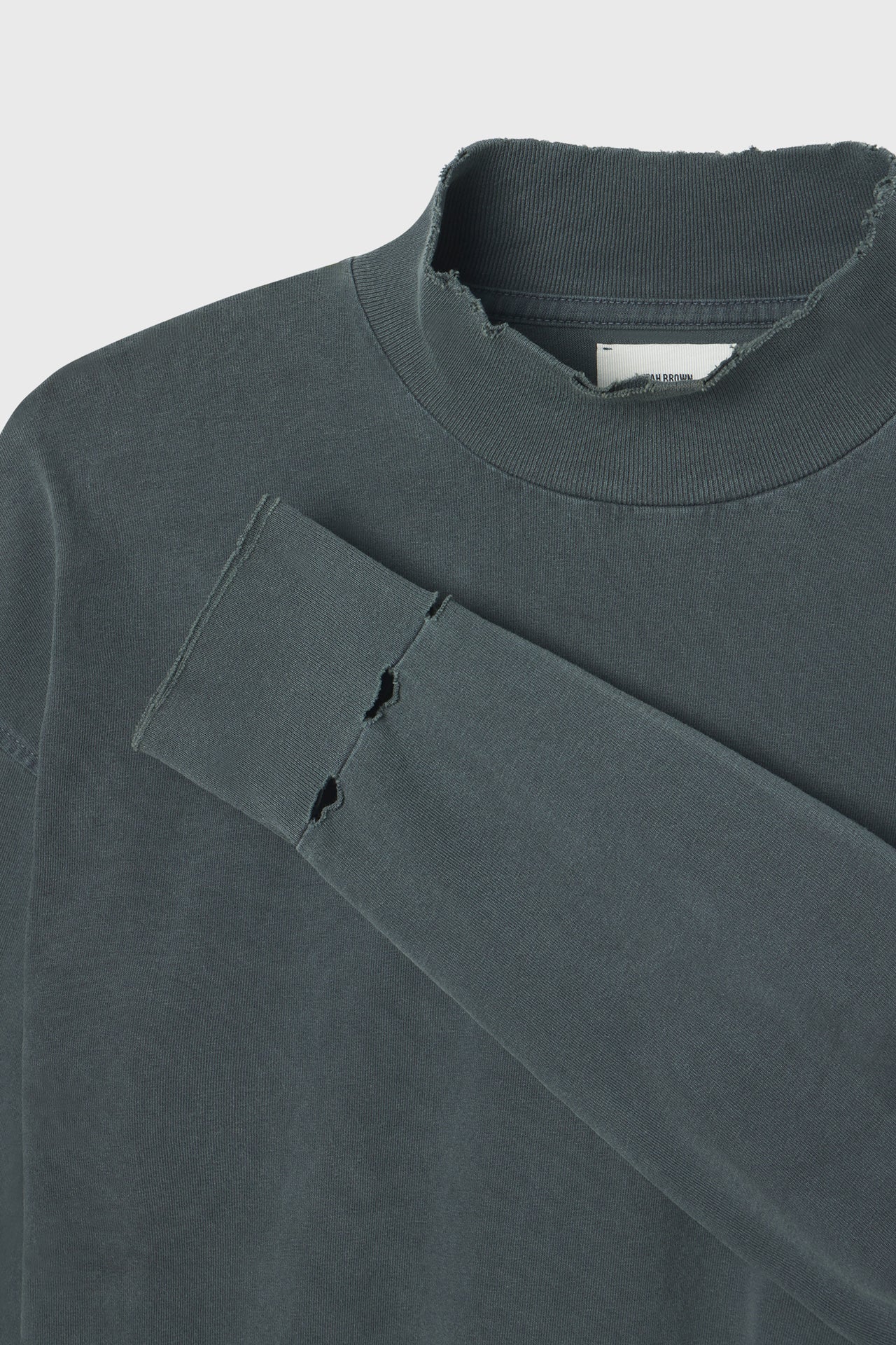 Close up detail front flat lay view the relaxed fit evergreen cotton Vintage Turtleneck Long Sleeve Top with thumbholes and torn seams at the cuff
