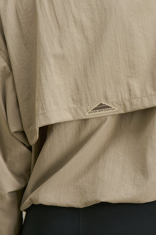 Close up detail back view of model posing in the relaxed fit desert sage nylon 3/4 Zip Windbreaker jacket with a structured collar and 3/4 zip neckline