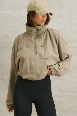 Front view of model posing in the relaxed fit desert sage nylon 3/4 Zip Windbreaker jacket with a structured collar and 3/4 zip neckline