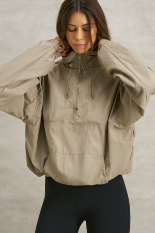 Front view of model posing in the relaxed fit desert sage nylon 3/4 Zip Windbreaker jacket with a structured collar and 3/4 zip neckline