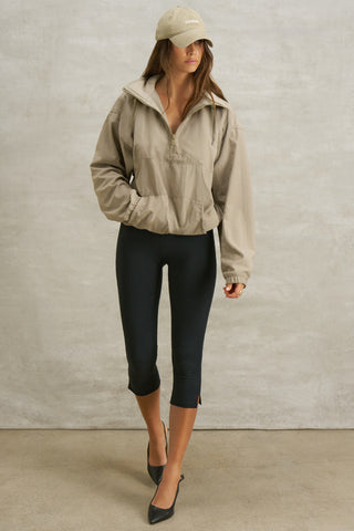 Full body front view of model posing in the relaxed fit desert sage nylon 3/4 Zip Windbreaker jacket with a structured collar and 3/4 zip neckline