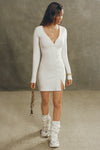 Full body front view of model posing in the soft and fitted natural luxe knit Asymmetrical Button Mini Dress with long sleeves,  a v-neckline and asymmetrical button-front details. 