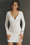 Front view of model posing in the soft and fitted natural luxe knit Asymmetrical Button Mini Dress with long sleeves,  a v-neckline and asymmetrical button-front details. 
