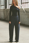 Full body front view of model posing in the fitted and lighweight black modal Asymmertical Long Sleeve top with an asymmetrical neckline and single-shoulder design