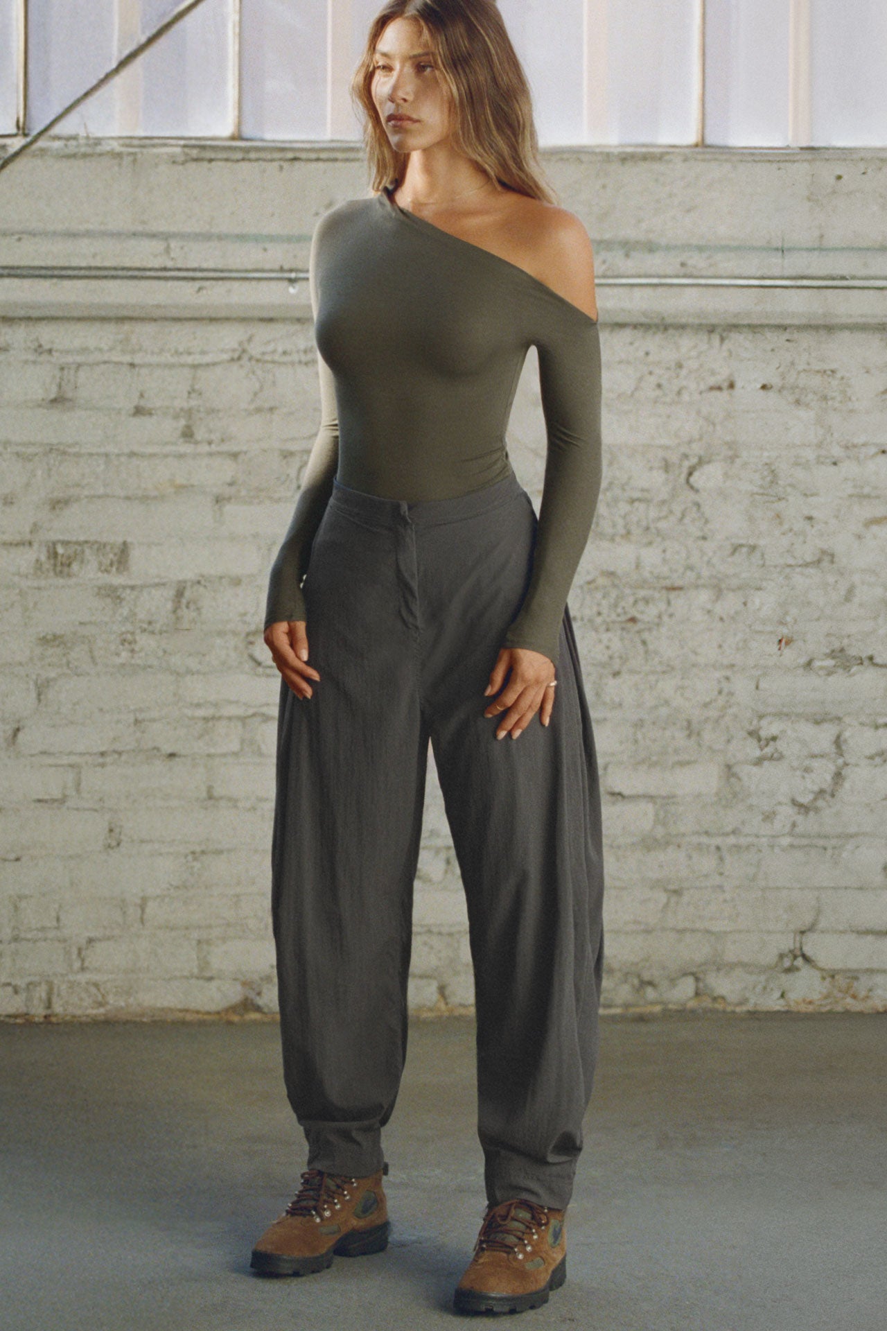 Full body front view of model posing in the fitted and lighweight spruce modal Asymmertical Long Sleeve top with an asymmetrical neckline and single-shoulder design