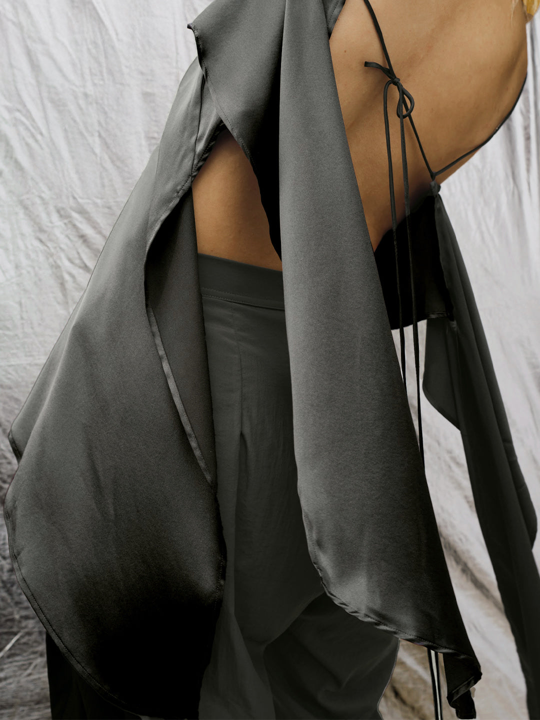 Close up detail back view of model posing the flowy iron Asymmetrical Silk Tank with a V-neckline, asymmetrical hem and an open back with thin, versatile straps that can tie straight or crisscross at the back