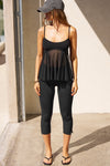 Full body front view of model posing in the flowy and sheer black polka dot lace Babydoll Tank with a scoop-neck tank with adjustable spaghetti straps and an open back design.