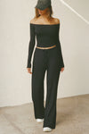 Full body front view of model posing in the fitted, slightly cropped black modal Bare Shoulder Long Sleeve top with a straight, off-the-shoulder neckline
