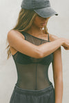 Front view of model posing in the reversible full-length sheer graphite mesh Bare Tank wearing it reversed so the front features a high neckline, with a vertical seam detail down the middle