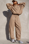 Full body front view of model posing in the oversized, horseshoe-style fawn nylon Barrel Pant with side pockets, zip fly, pleated sides and adjustable snap closures at the ankle.