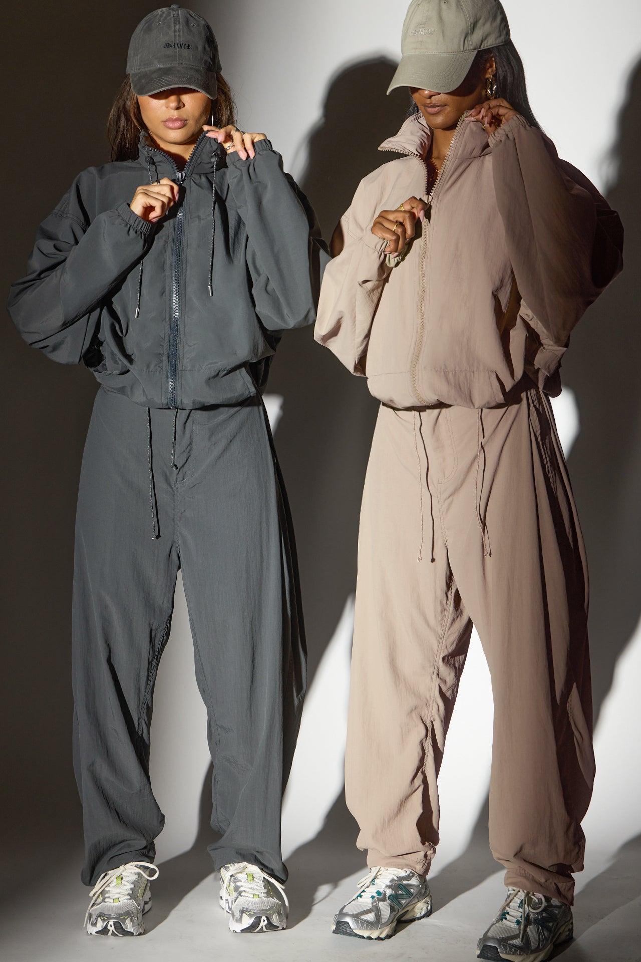 Two models posing in a jet nylon and fawn  nylon Classic Windbreaker Jacket and Barrel Pant sets