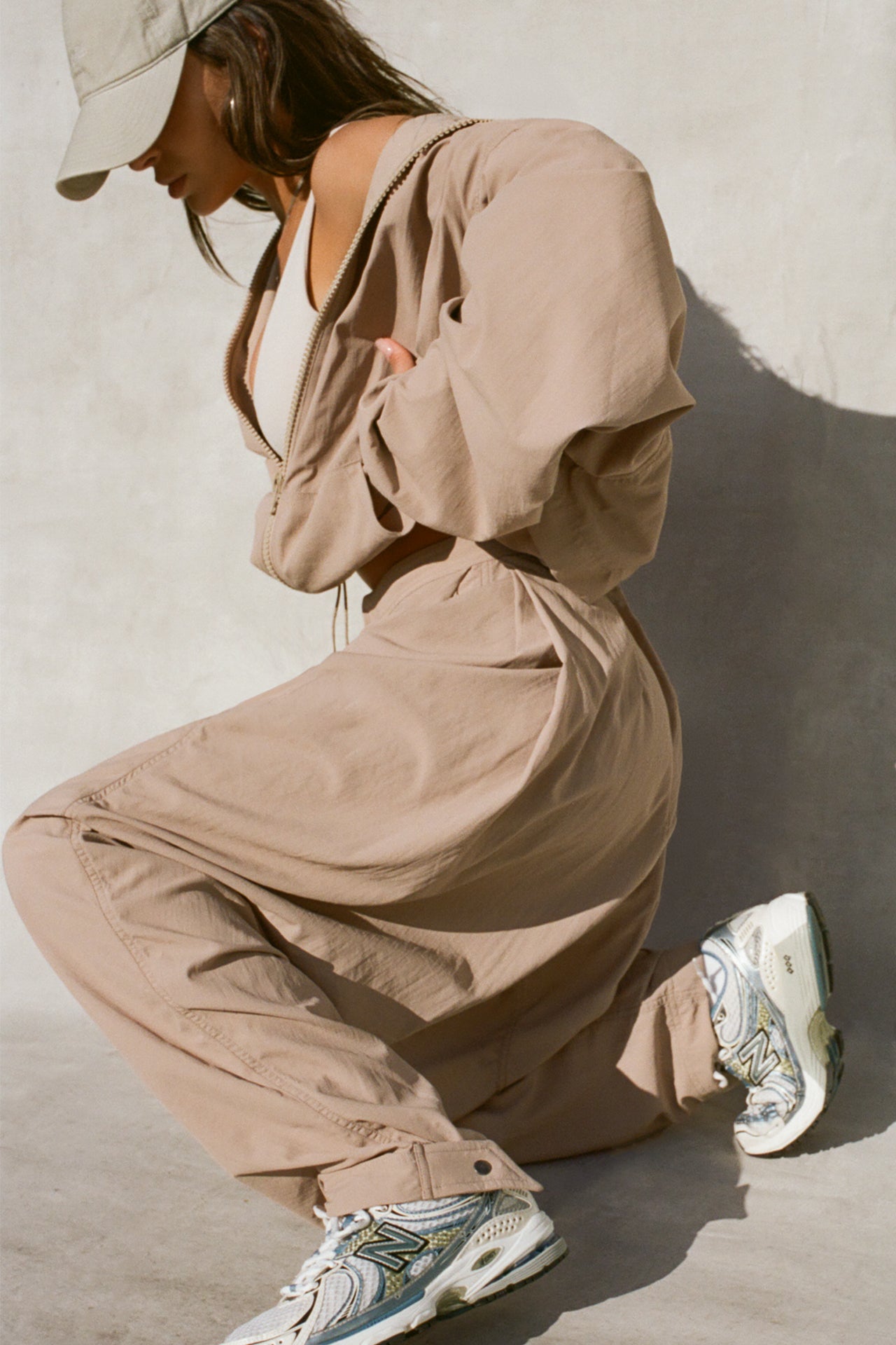 Side view of model posing in the oversized, horseshoe-style fawn nylon Barrel Pant with side pockets, zip fly, pleated sides and adjustable snap closures at the ankle.