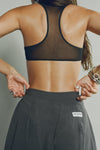 Back view of model posing in the oversized, horseshoe-style jet nylon Barrel Pant with side pockets, zip fly, pleated sides, adjustable snap closures at the ankle and a JOAH BROWN logo on the back below the waistline.