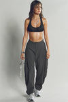 Full body front view of model posing in the oversized, horseshoe-style jet nylon Barrel Pant with side pockets, zip fly, pleated sides and adjustable snap closures at the ankle.