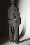 Full body back view of model posing in the oversized, horseshoe-style jet nylon Barrel Pant with side pockets, zip fly, pleated sides, adjustable snap closures at the ankle and a JOAH BROWN logo on the back below the waistline.